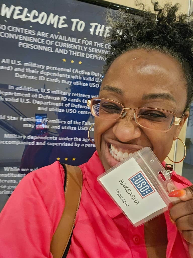 Founder NaKeasha Garth smiling with her USO volunteer badge at the USO center in Tampa Bay