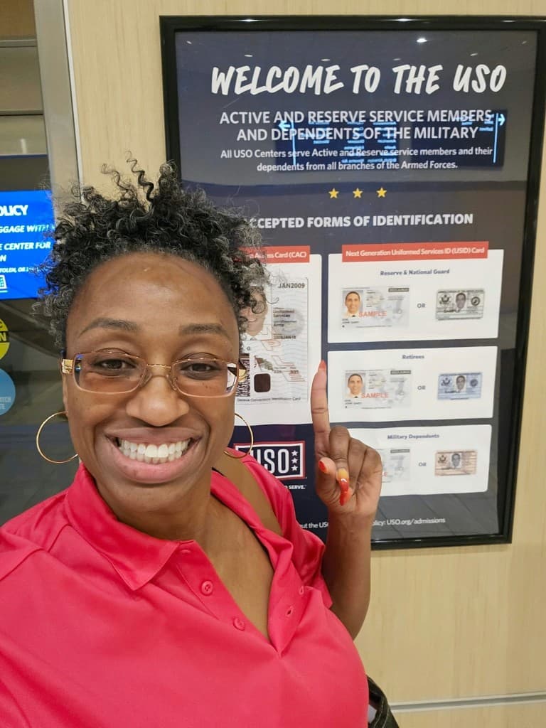 Founder NaKeasha Garth pointing to the Welcome to the USO sign at the USO center in Tampa Bay